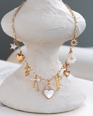 Gold necklace with various charms on a white stand