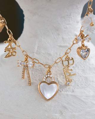 Gold necklace with various charms on a textured white surface