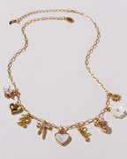 Gold necklace with various charms on a light gray background