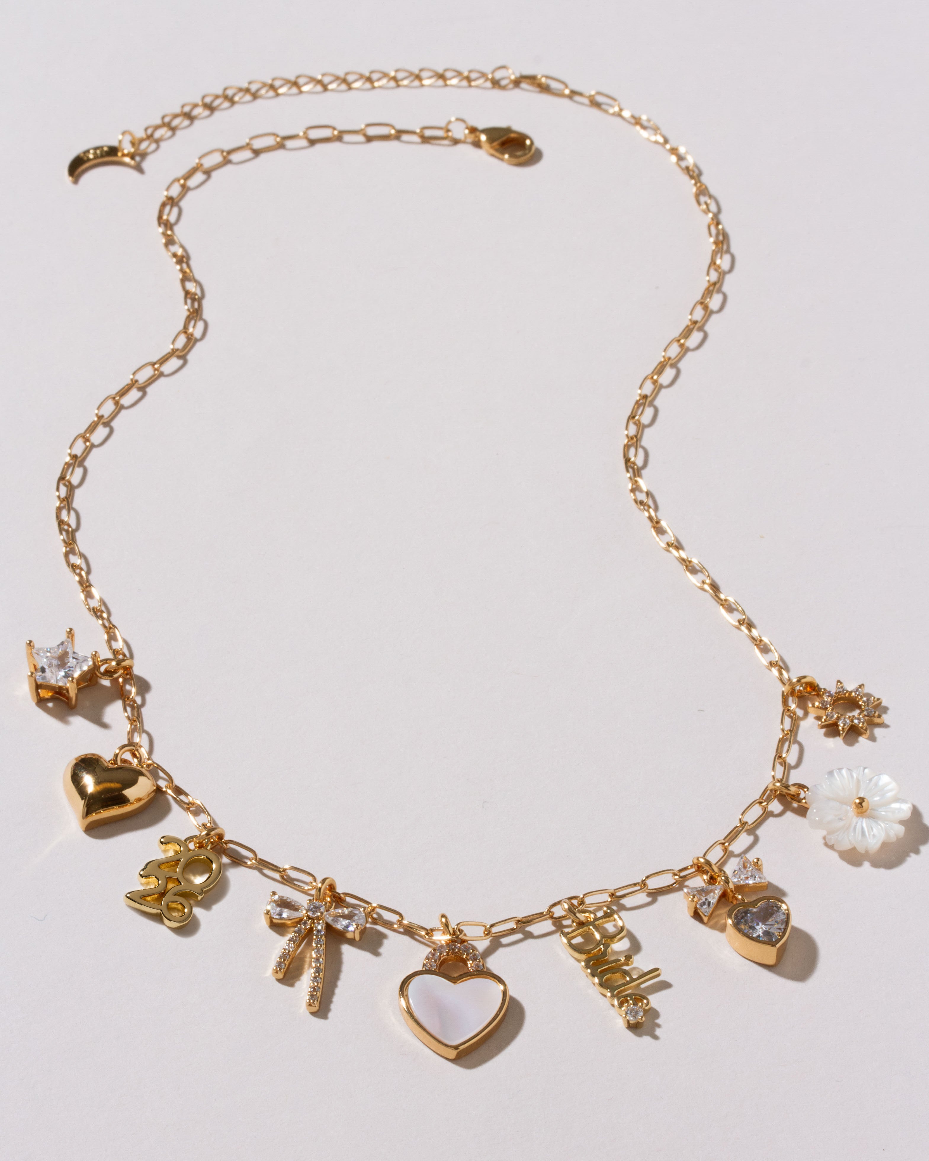 Gold necklace with various charms on a light gray background