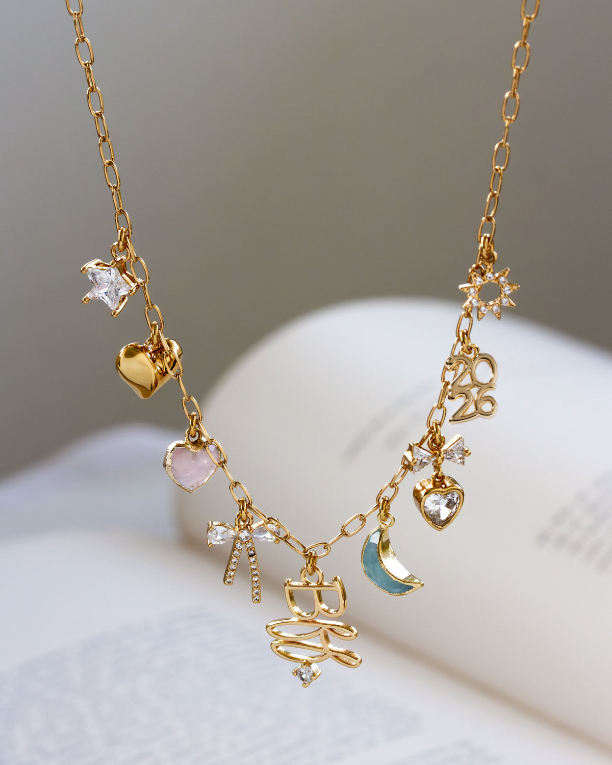 Gold necklace with various charms on a white surface