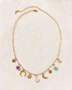 Gold charm necklace with Amethyst, Multistone star, moon, and sun charms on a paperclip chain.