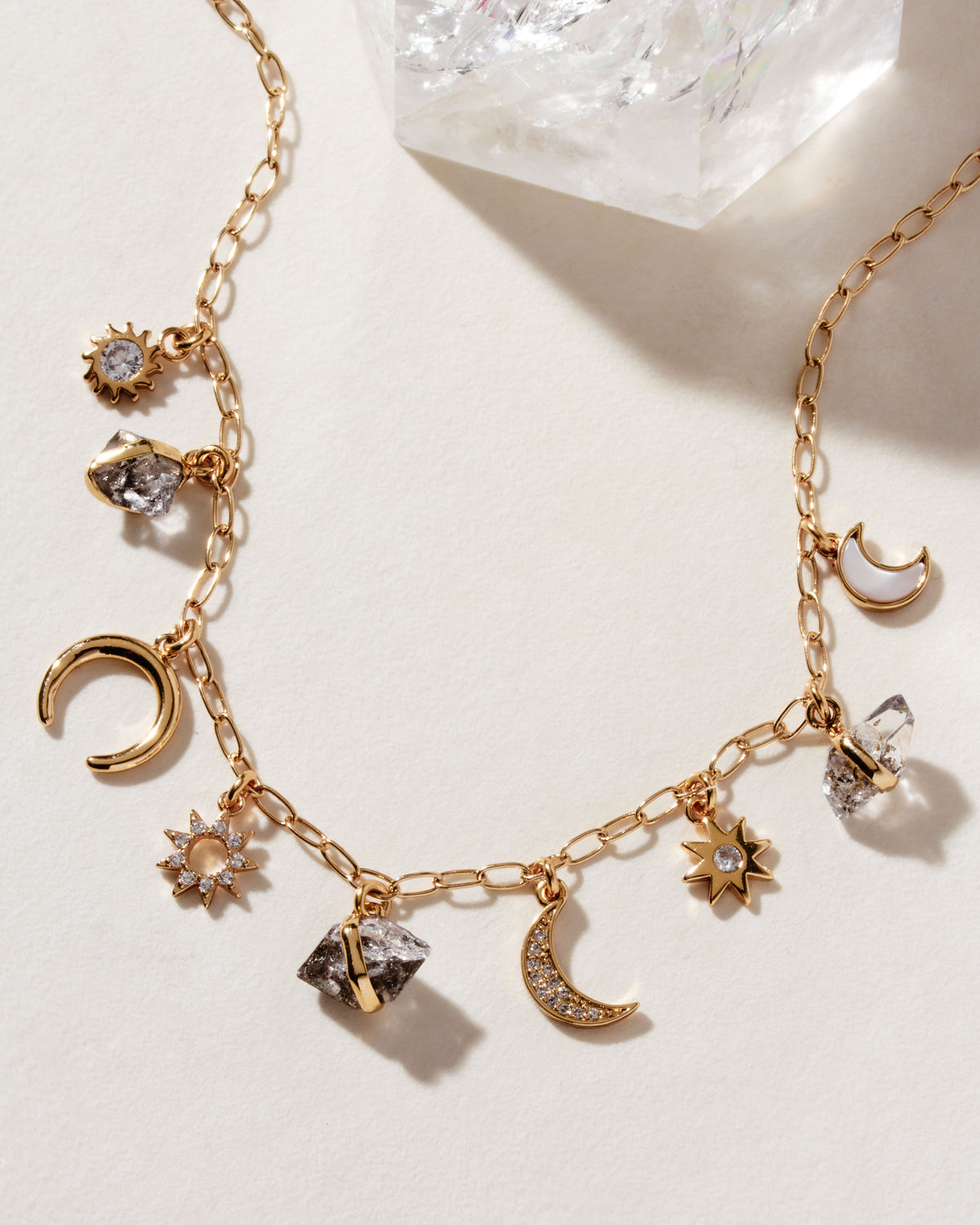 Gold charm necklace with Herkimer quartz, mother-of-pearl, and celestial charms