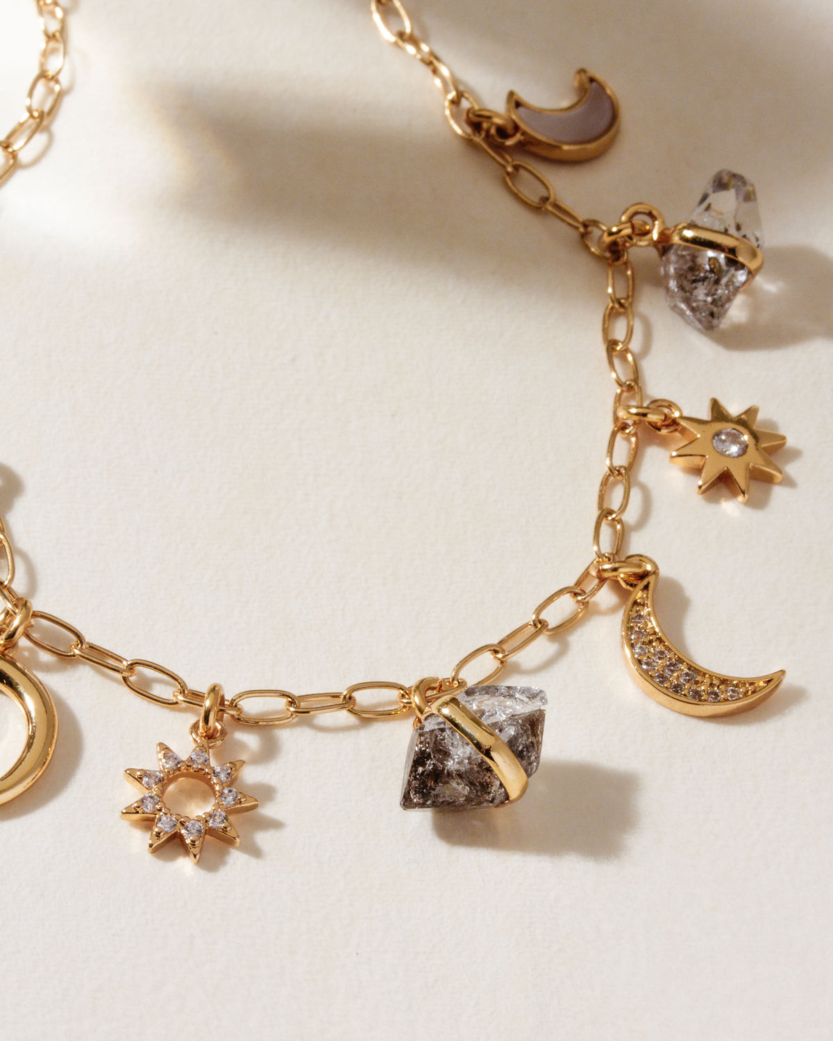Gold charm necklace with black onyx, Herkimer quartz, moonstone, and celestial charms