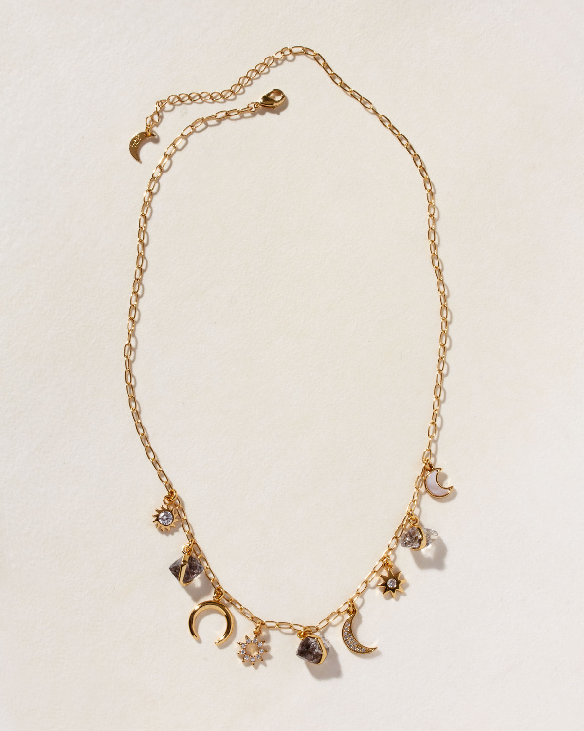 Gold charm necklace with black onyx, Herkimer quartz, moonstone, and celestial charms