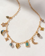 A gold charm necklace with various celestial and heart-shaped charms, with labradorite stones.