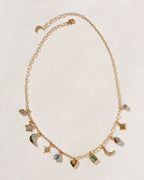 A gold charm necklace with various celestial and heart-shaped charms, with labradorite stones.