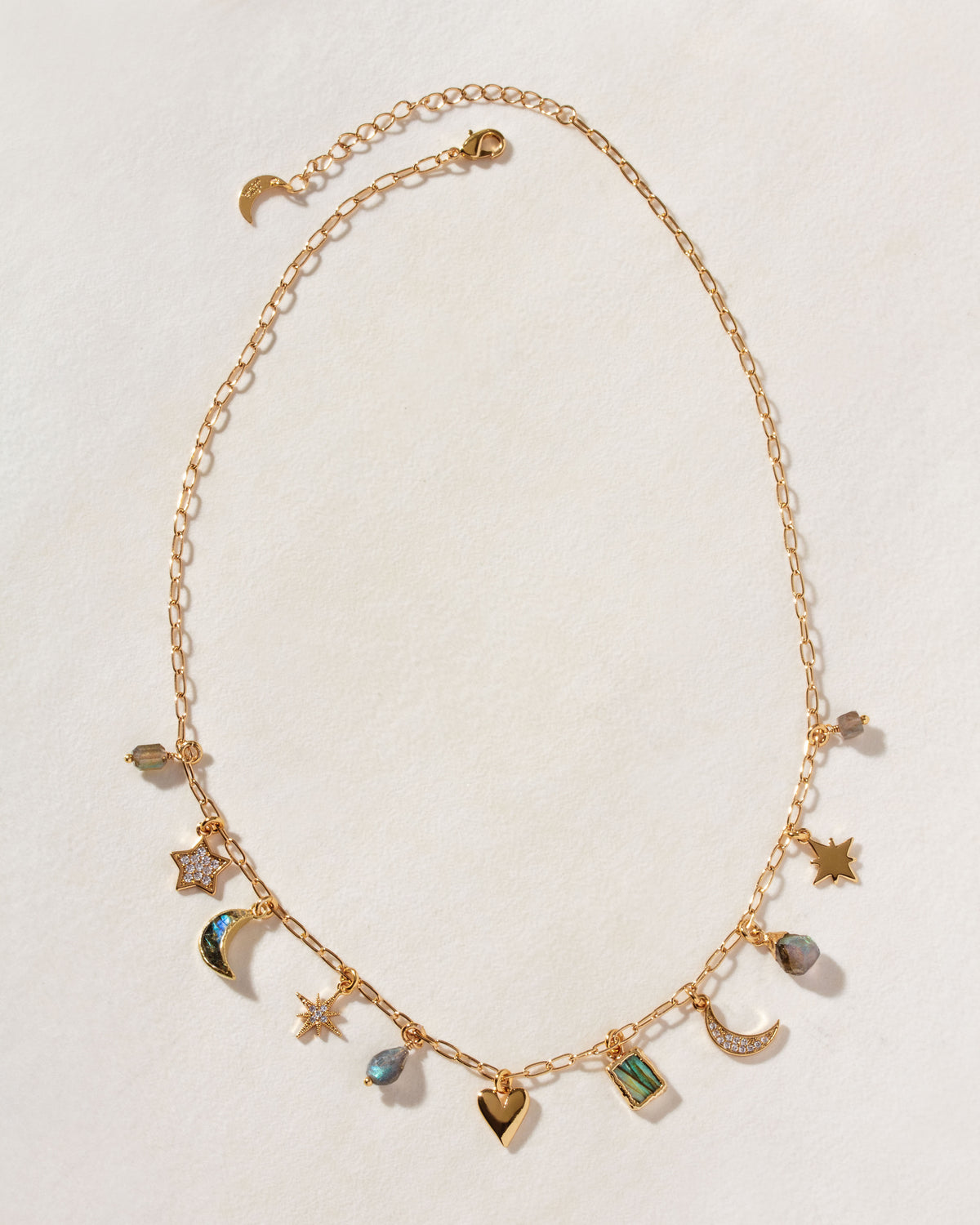 A gold charm necklace with various celestial and heart-shaped charms, with labradorite stones.