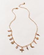 Gold chain necklace with many star, and coffee moonstone beads on a white surface.