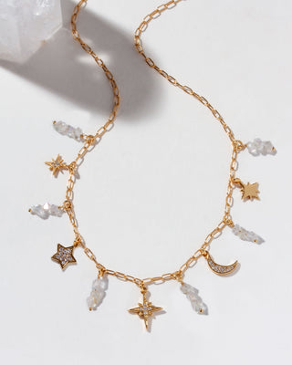 Gold necklace with cz star and moon charms and quartz beads on a light background