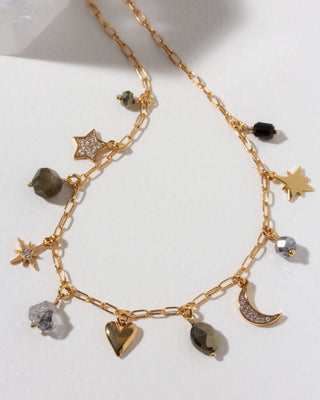 Gold necklace with many celestial gold and cz and gemstone charms on a light background