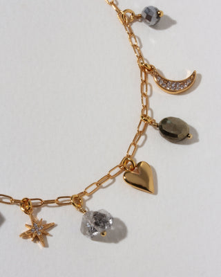 Gold necklace with many celestial gold and cz and gemstone charms on a light background