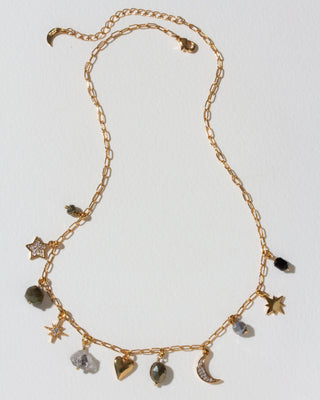 Gold necklace with many celestial gold and cz and gemstone charms on a light background