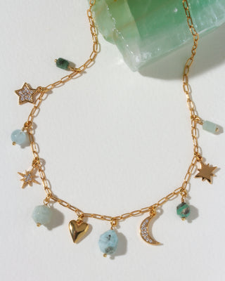 Gold necklace with many celestial gold and cz and gemstone charms on a light background