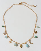 Gold necklace with many celestial gold and cz and gemstone charms on a light background
