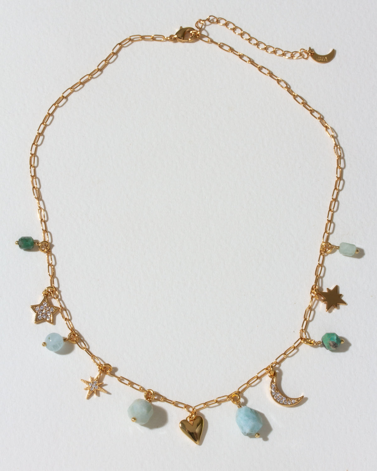 Gold necklace with many celestial gold and cz and gemstone charms on a light background