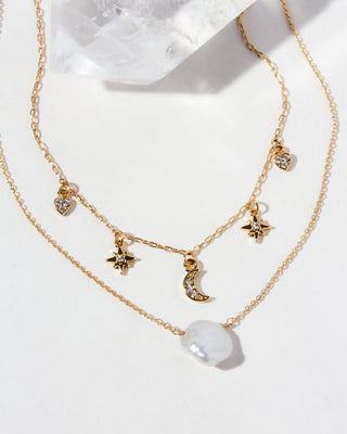 Gold necklace with star and moon charms on a white background