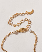 Close up of gold plated necklace showing lobster clasp, extension chain, and pearl beads.