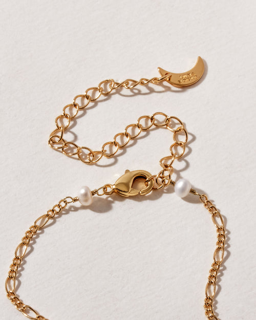 Close up of gold plated necklace showing lobster clasp, extension chain, and pearl beads.