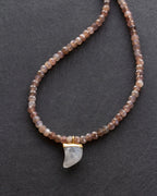 Necklace with beaded chain and crescent moon pendant on a dark background