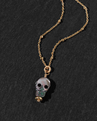 A gold chain necklace featuring a skull pendant.