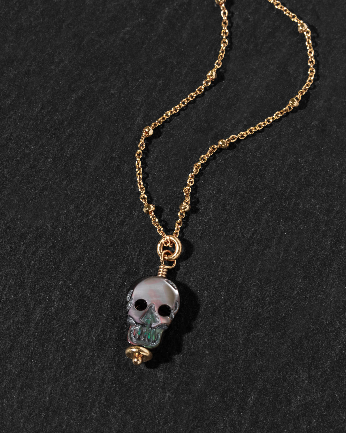 A gold chain necklace featuring a skull pendant.