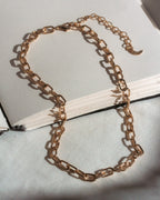 Gold chain necklace on a light gray surface