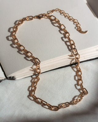 Gold chain necklace on a light gray surface