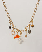 Gold necklace with various charms on a light gray background