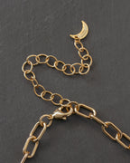 Gold chain necklace extender chain with a crescent moon logo charm on a dark gray background