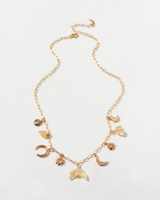 Gold necklace with many celestial gold and cz and citrine gemstone charms on a light background