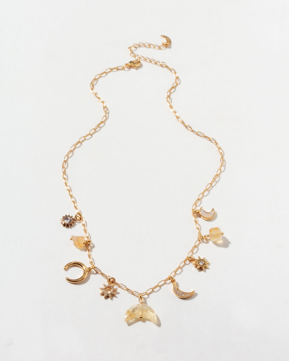 Gold necklace with many celestial gold and cz and citrine gemstone charms on a light background