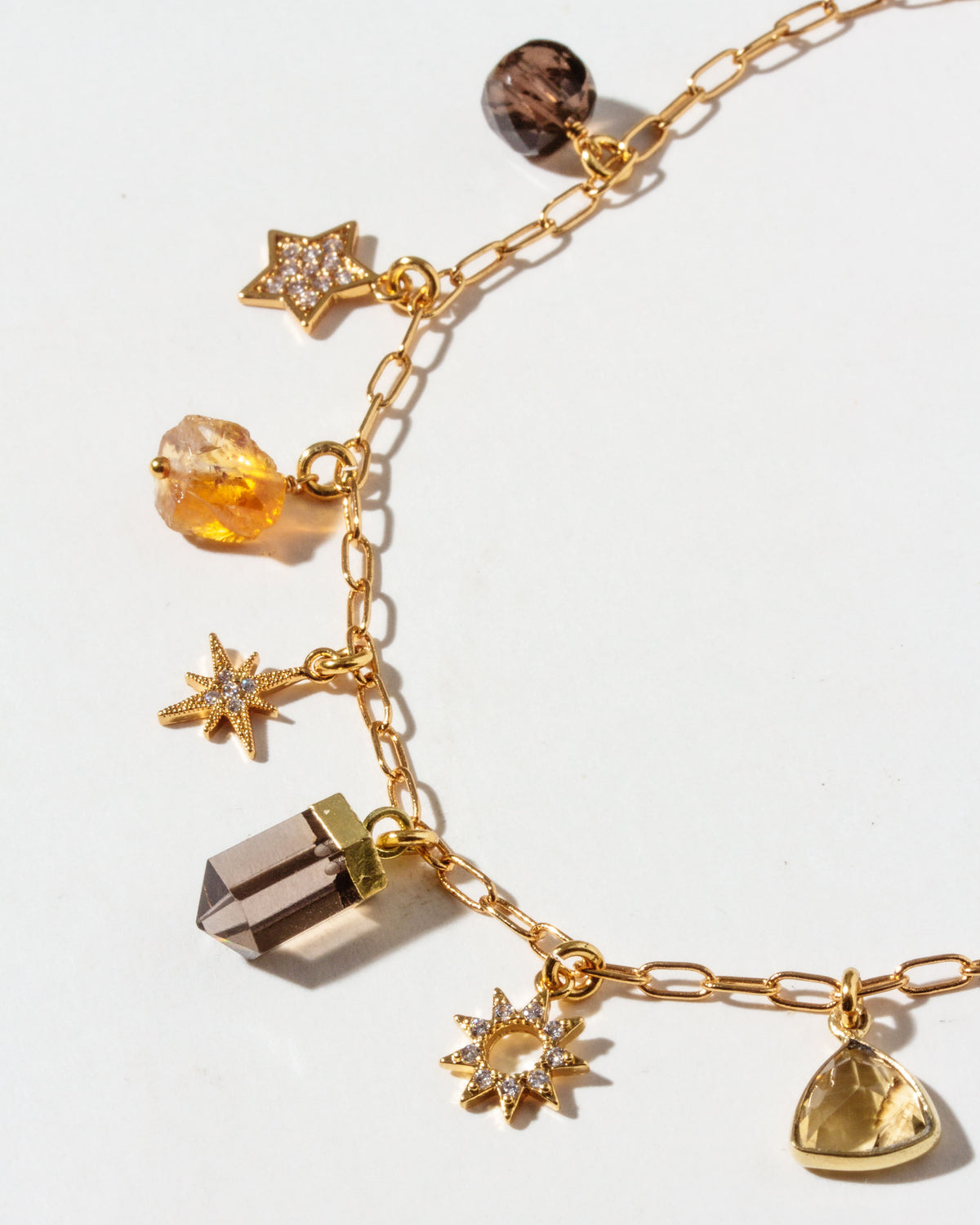 Gold necklace with various CZ, Smoky Quartz, and Citrine charms on a white background