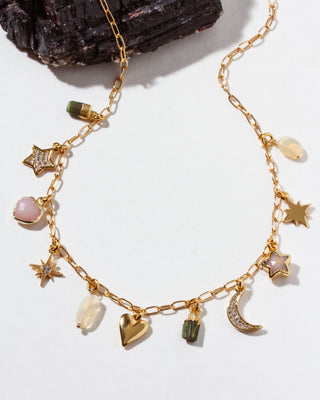Gold necklace with various charms on a white background