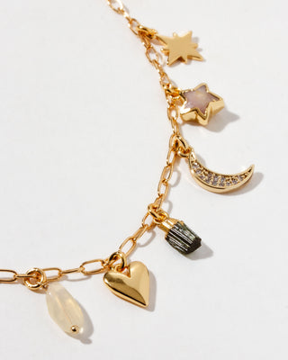 Closeup of gold necklace with various charms on a white background