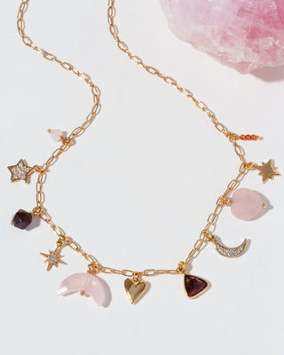 Gold chain necklace with various gemstone charms on a light background