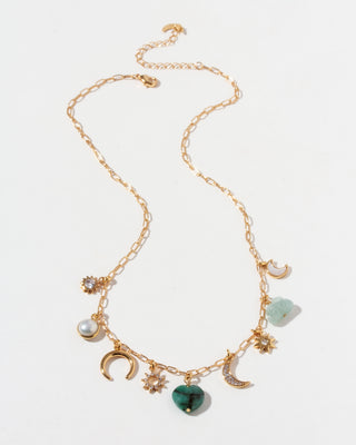 Gold necklace with various CZ, emerald, mother-of-pearl, aquamarine, and pearl charms on a white background.