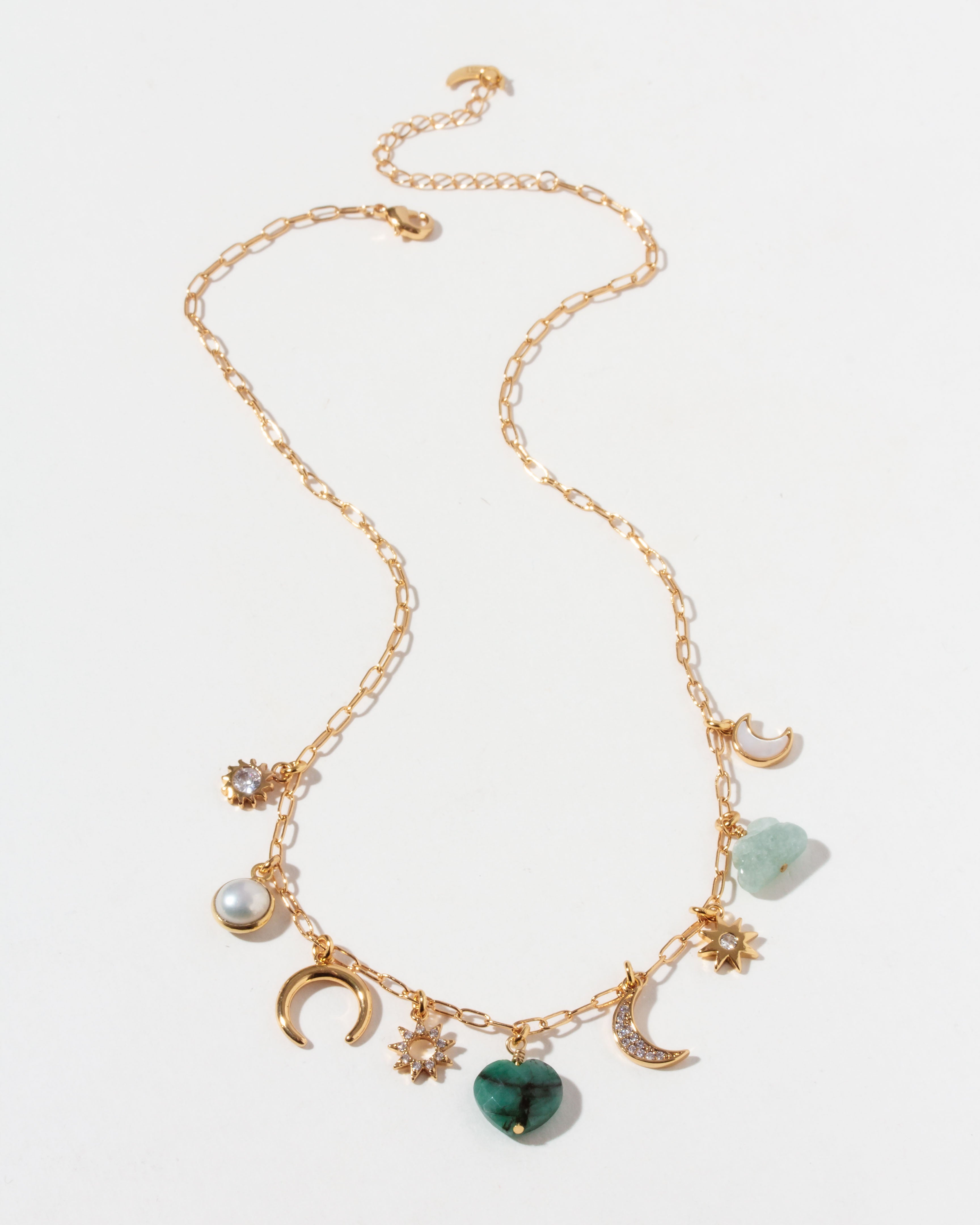 Gold necklace with many different shaped CZ, emerald, mother-of-pearl, aquamarine, and pearl charms