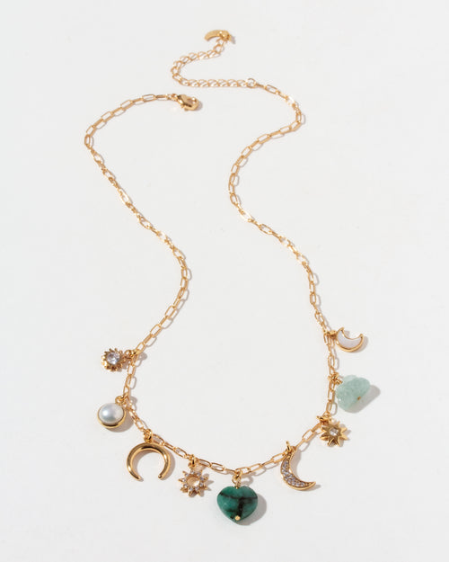 Gold necklace with many different shaped CZ, emerald, mother-of-pearl, aquamarine, and pearl charms