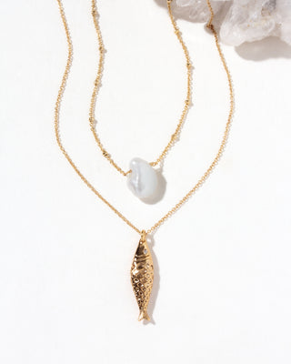 Gold necklace set with a fish and keshi pearl pendants on a white background