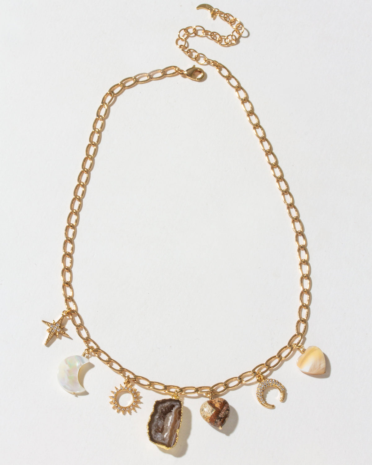 Gold chain necklace with various charms on a light gray background