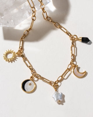 Onyx & Moonlight Charm Necklace with sun, pearl, and onyx charms on a gold chain.