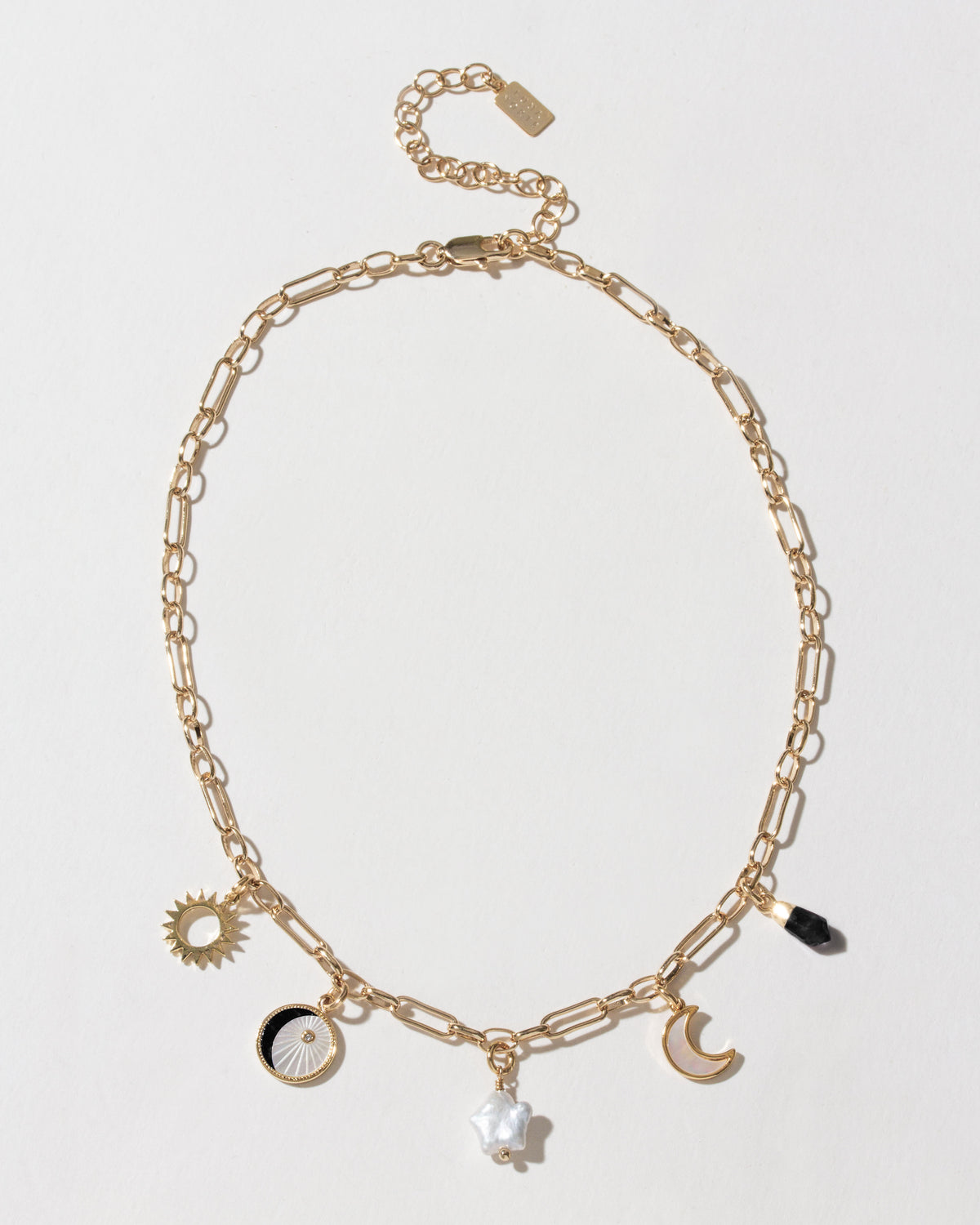 Gold chain necklace with onyx point, pearl star, and sun/moon charms.