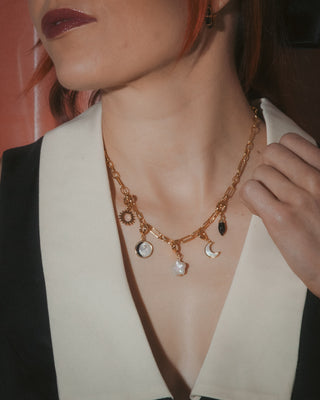 Necklace with charms worn by a person, focusing on the jewelry.