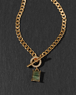 A gold chain necklace with a toggle clasp featuring a small cubic zirconia-studded toggle ring and a rectangular green labradorite gemstone pendant.