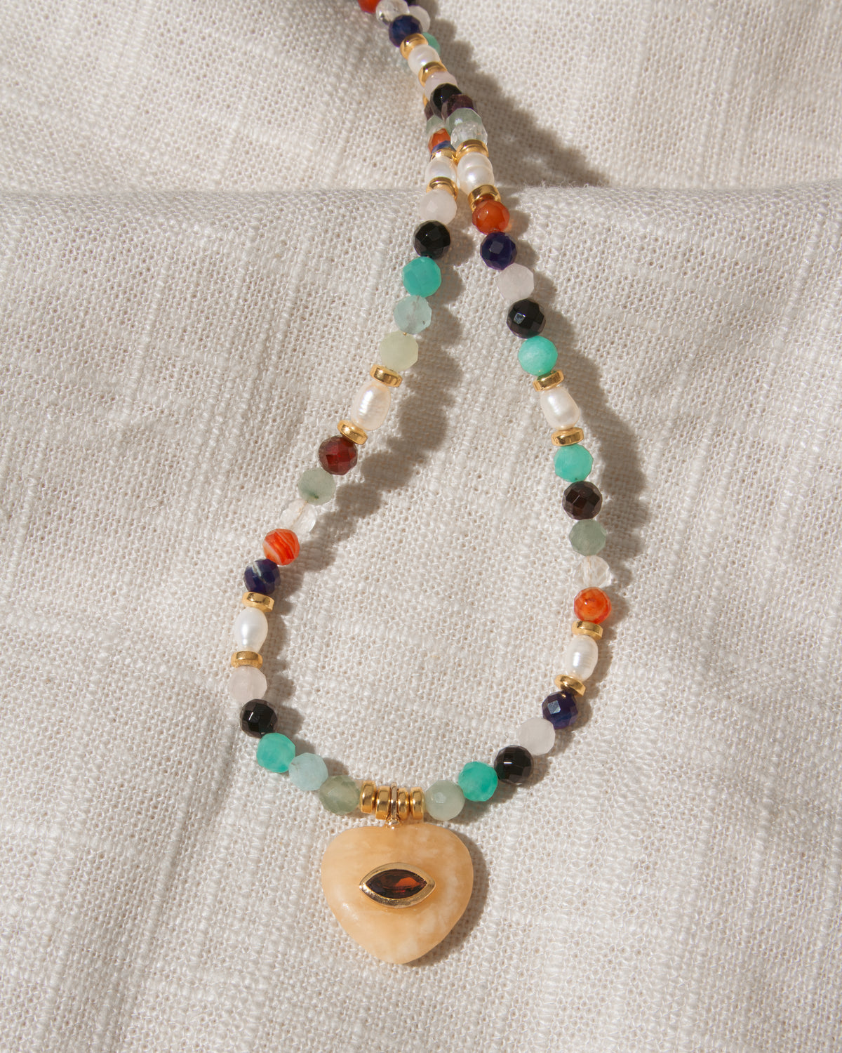 Multicolor faceted gemstone beaded necklace with yellow calcite heart centered with eye shaped CZ center.
