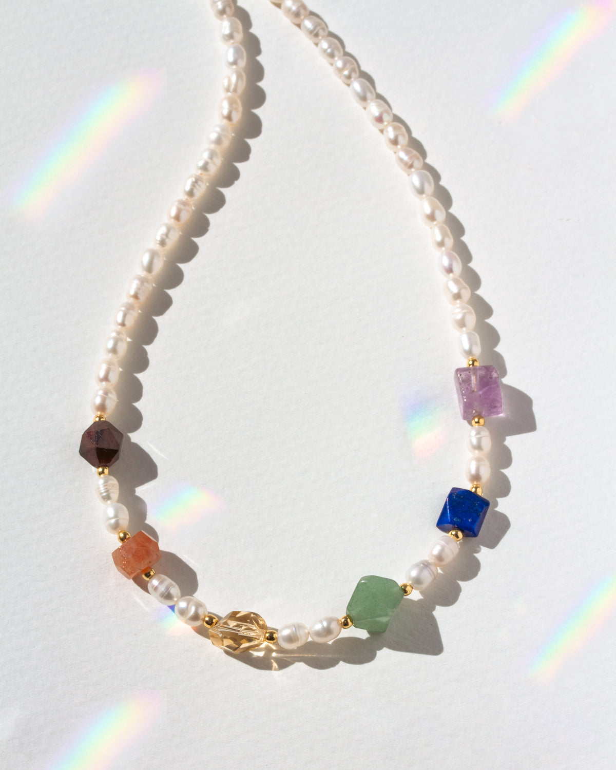 Necklace with multicolored beads on a white background with rainbow shadows