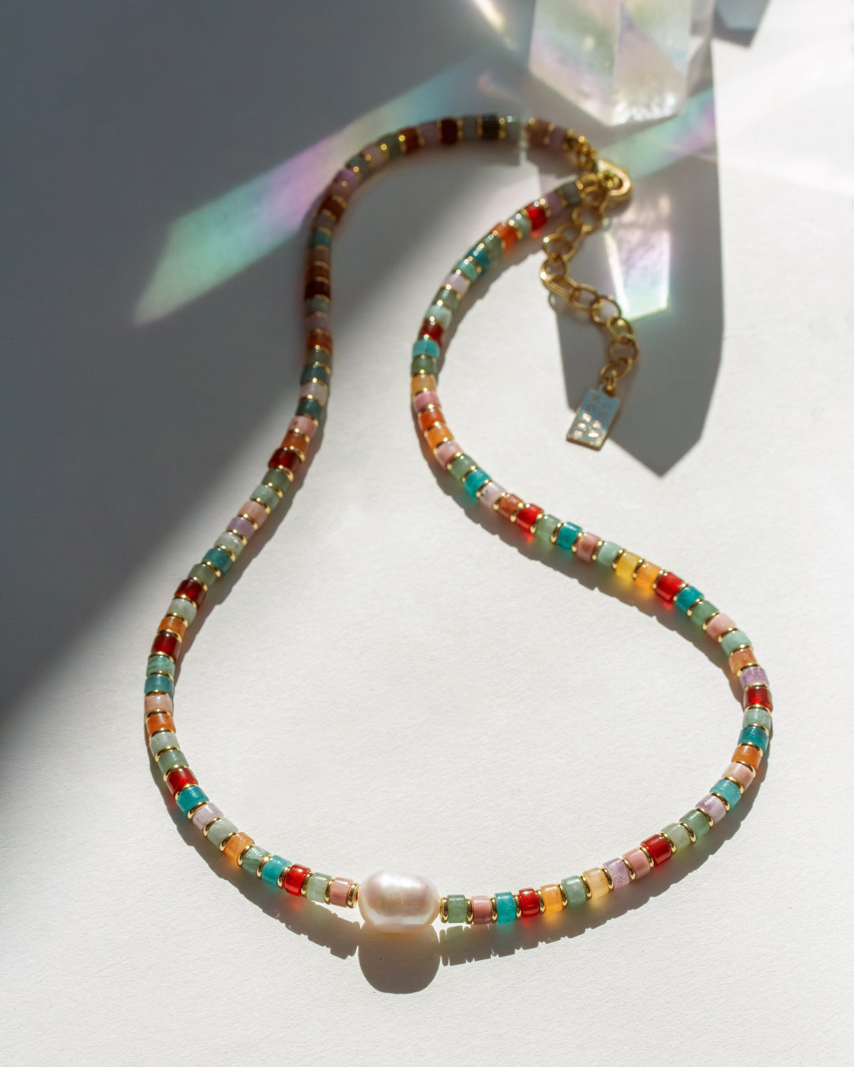 Colorful beaded necklace with a pearl on a white surface