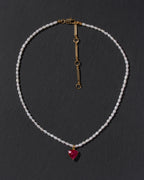 Necklace with a red inverted triangle pendant on a dark background