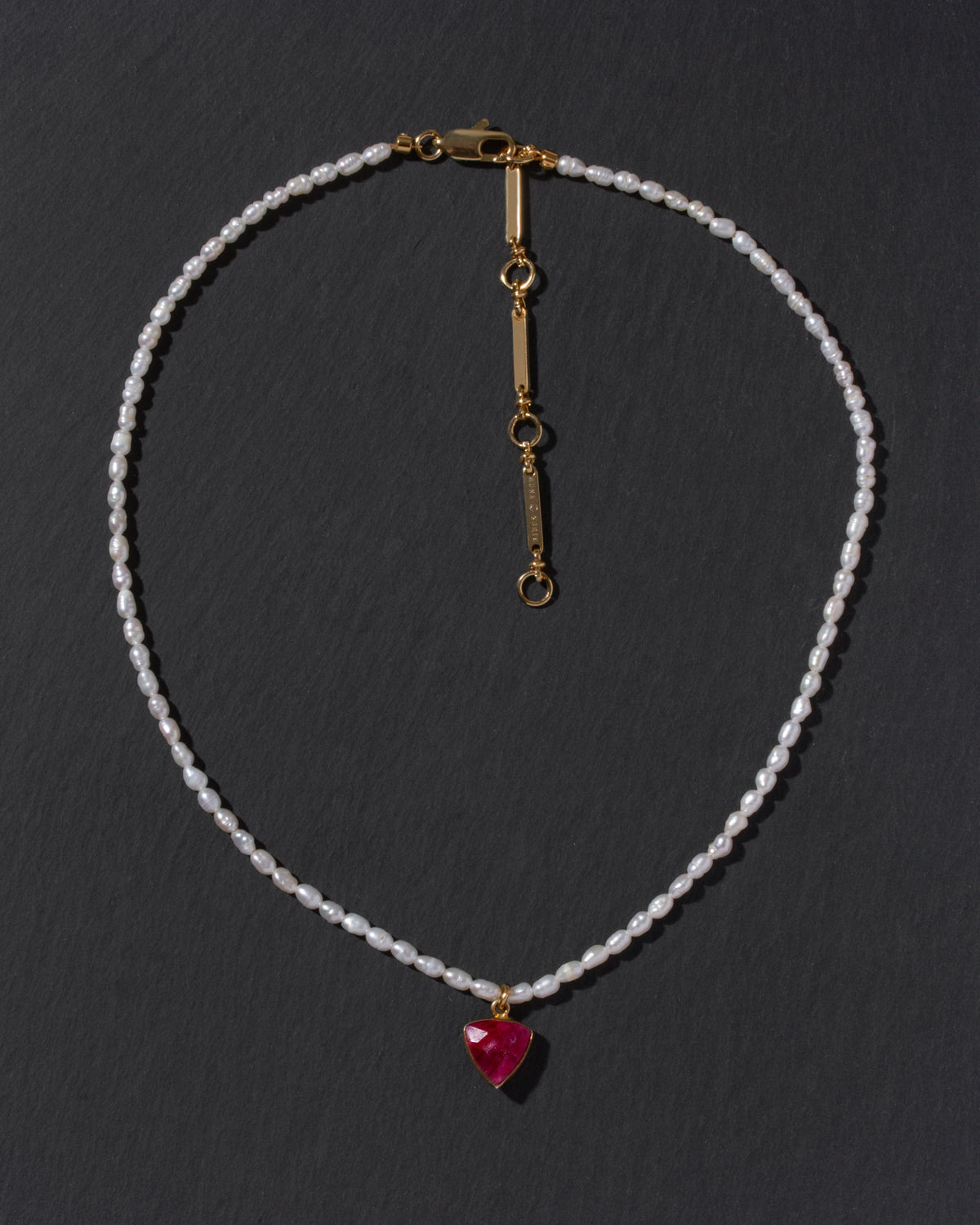 Necklace with a red inverted triangle pendant on a dark background